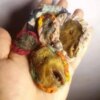 A close-up of three small, round, fabric-covered objects. The objects are in various shades of brown, yellow, and red. The fabric is patterned with flowers and other designs. — Khodamdjin