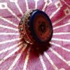 A gold-toned ring with an oval, dark blue stone. The stone features a gold-colored design with a central knot and stars. The ring has intricate filigree detailing on the sides and a gold band. — Khodamdjin