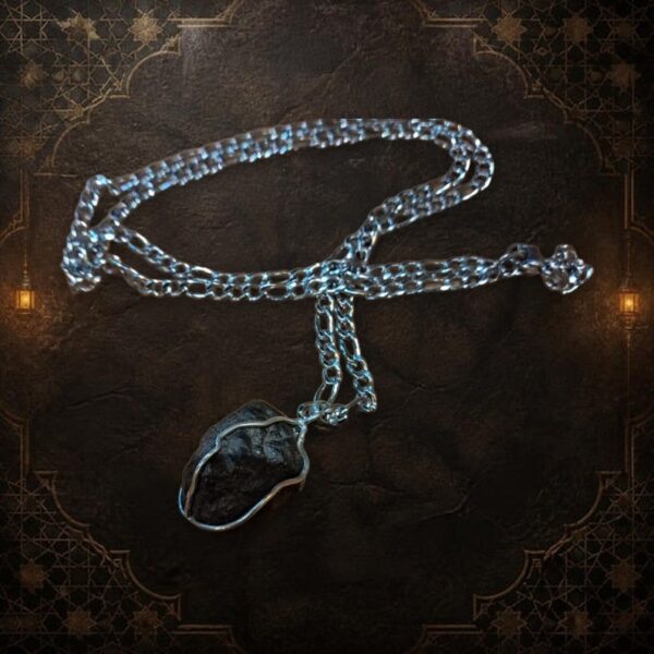 A silver-toned metal chain necklace featuring a dark, textured, irregular-shaped stone pendant secured within a thin silver-colored wire wrap. The chain consists of elongated oval links connected by smaller circular links in a classic pattern. — Khodamdjin